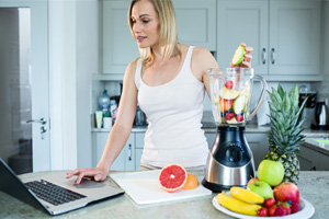 Mujer cocinando consultando un portátil